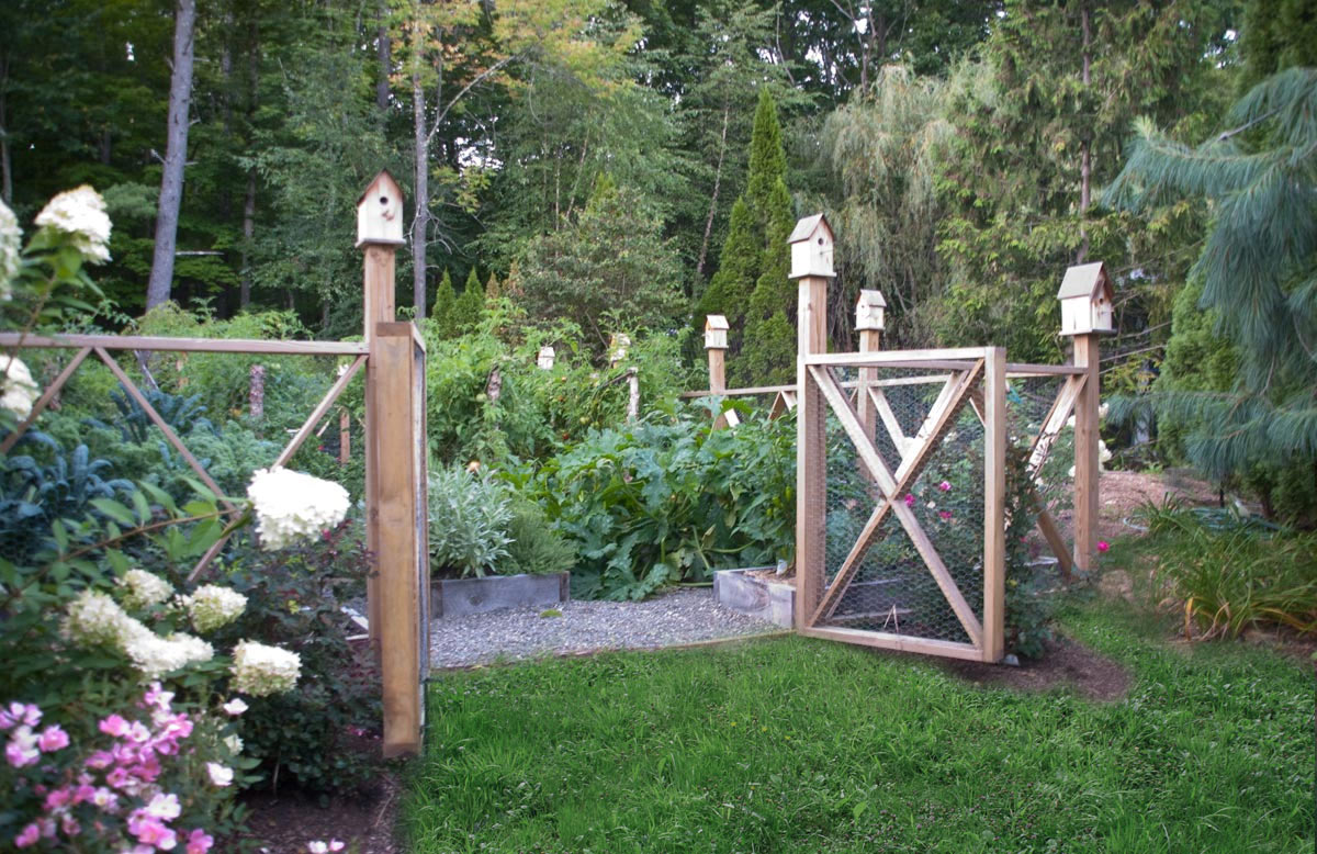 A Cedar Decorative Fence and Birdhouses Surround an Organic Vegetable Garden